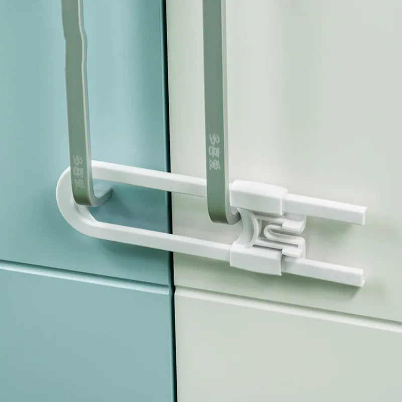 Close-up of a white cabinet lock mechanism with gray U-shaped handles and mounting plate.