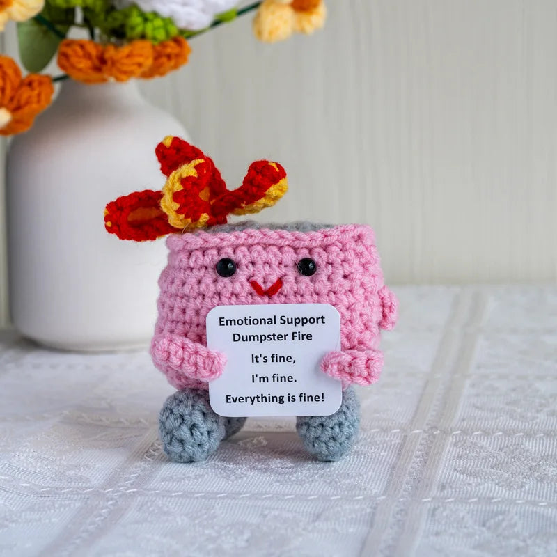 Handmade crochet dumpster fire doll with bright orange and red features sitting on a white surface.