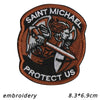 A brown embroidered patch featuring the text SAINT MICHAEL PROTECT US with an archangel design.