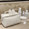 A white Miffy cartoon rabbit cosmetic storage bag with a zipper and a round white compact is displayed on a marble surface.