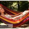 A woman relaxing in a colorful outdoor hammock in a wooded setting.