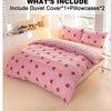A pink strawberry print duvet cover set with two pillowcases displayed on a bed in a bright room.