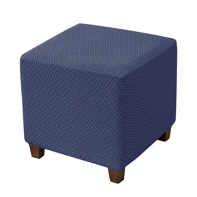 A dark blue stretch jacquard ottoman slipcover with an elastic edge.