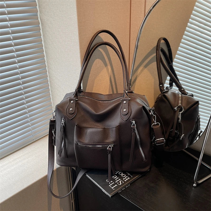 A dark brown soft leather plaid crossbody bag with an adjustable strap resting on a dark surface.