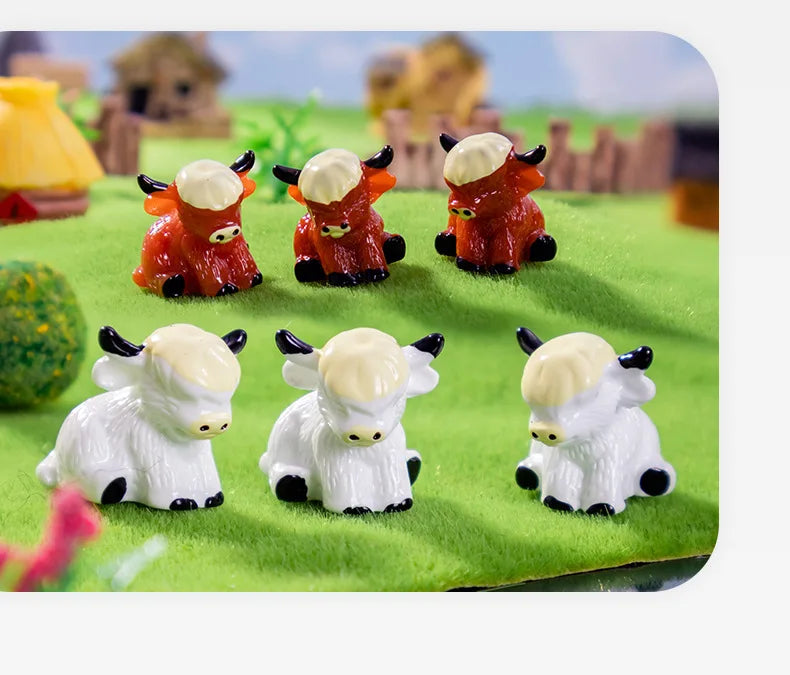 A collection of adorable resin Highland cow figurines in orange and white colors displayed on green grass.