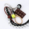 A metal 8-ball keychain featuring a black finish, attached to a leather strap and a chocolate bar.