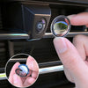 A hand is holding a clear lens protector for a car camera, showing a view of greenery.