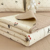 A stack of floral quilted fabric covers and a white stuffed animal resting on a beige surface.