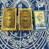 A set of gold foil tarot cards and guidebook featuring The Fool card on a blue patterned cloth.