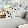 A light gray elegant jacquard sofa slipcover with an elastic fit shown in a bright, modern living room.