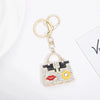 Gold chain keychain featuring a square handbag charm decorated with black and gold patterns and colorful rhinestones