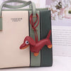 A light beige and olive green PU leather handbag with a red dachshund keychain charm.