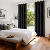 Blackout curtain panels with grommet top covering a window in a bright bedroom setting.
