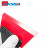 A red plastic windshield ice scraper and squeegee being held by a white glove.