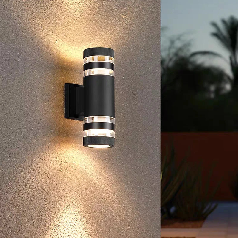 Modern black LED wall sconce with multiple light strips illuminating a textured wall outdoors