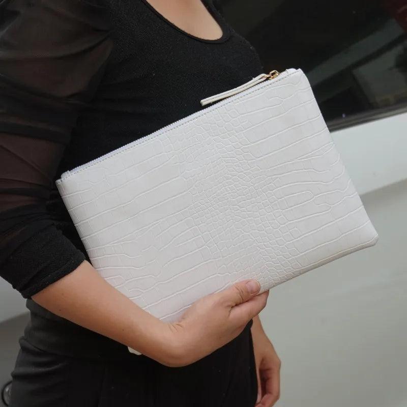 A woman holds a white crocodile-embossed PU leather envelope clutch against a black top.