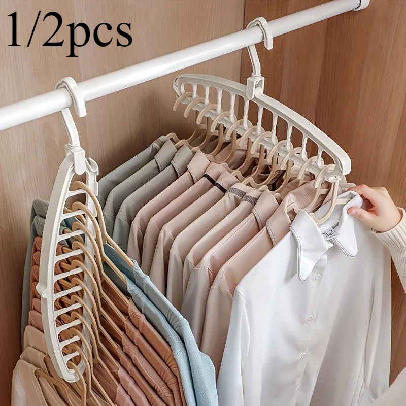 A white clothes hanger with multiple holes is displayed on a white rod, showing various colored shirts and blouses.