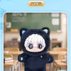 A dark blue plush doll resembling a cat with white hair and glasses, displayed in a classroom setting.