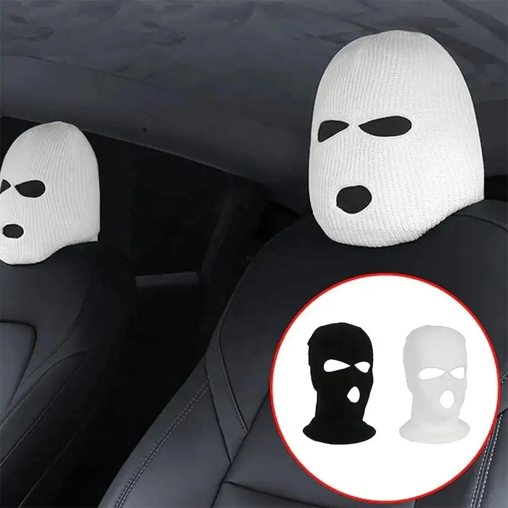 White and black ski mask car headrest covers placed on a dark car seat.