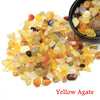 Yellow agate tumbled crystal stone chips scattered on a white background.