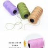 Three spools of purple, green, and tan polyester knitting yarn with loose strands.