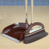 A brown broom and dustpan set with a floor wiper resting on a wooden surface.