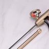 A close-up view of a brass adjustable foam spray gun with a black hose and nozzle on a white surface.