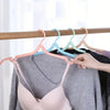 A close-up of a pink bra being hung on a wooden clothes hanger with a light blue hook.