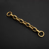 A gold-colored acrylic chain strap for a handbag, laid diagonally on a dark surface.