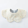 A light yellow cotton baby feeding bib with a textured surface and scattered colorful dots.