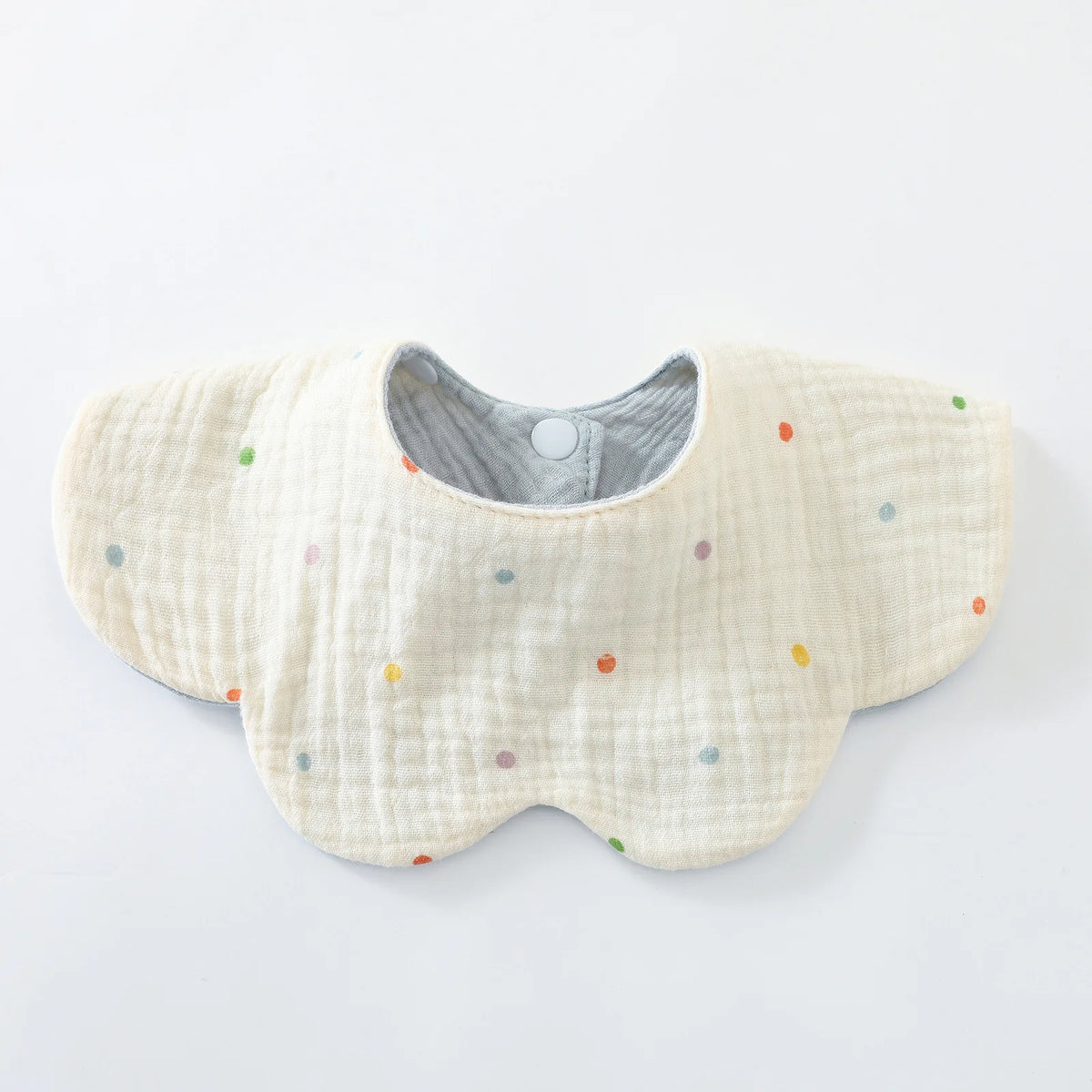A light yellow cotton baby feeding bib with a textured surface and scattered colorful dots.