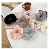 A collection of plush coil hair ties in various shades of gray, pink, and black are displayed on a white surface.