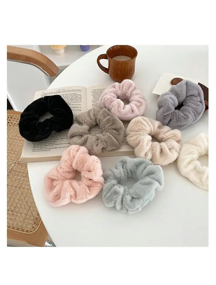 A collection of plush coil hair ties in various shades of gray, pink, and black are displayed on a white surface.