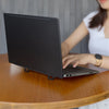 A person is using an aluminum portable laptop stand with adjustable legs on a wooden table.