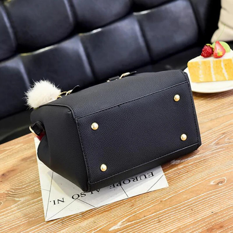 A black vintage PU leather tassel shoulder bag with a gold-toned strap resting on a wooden surface.