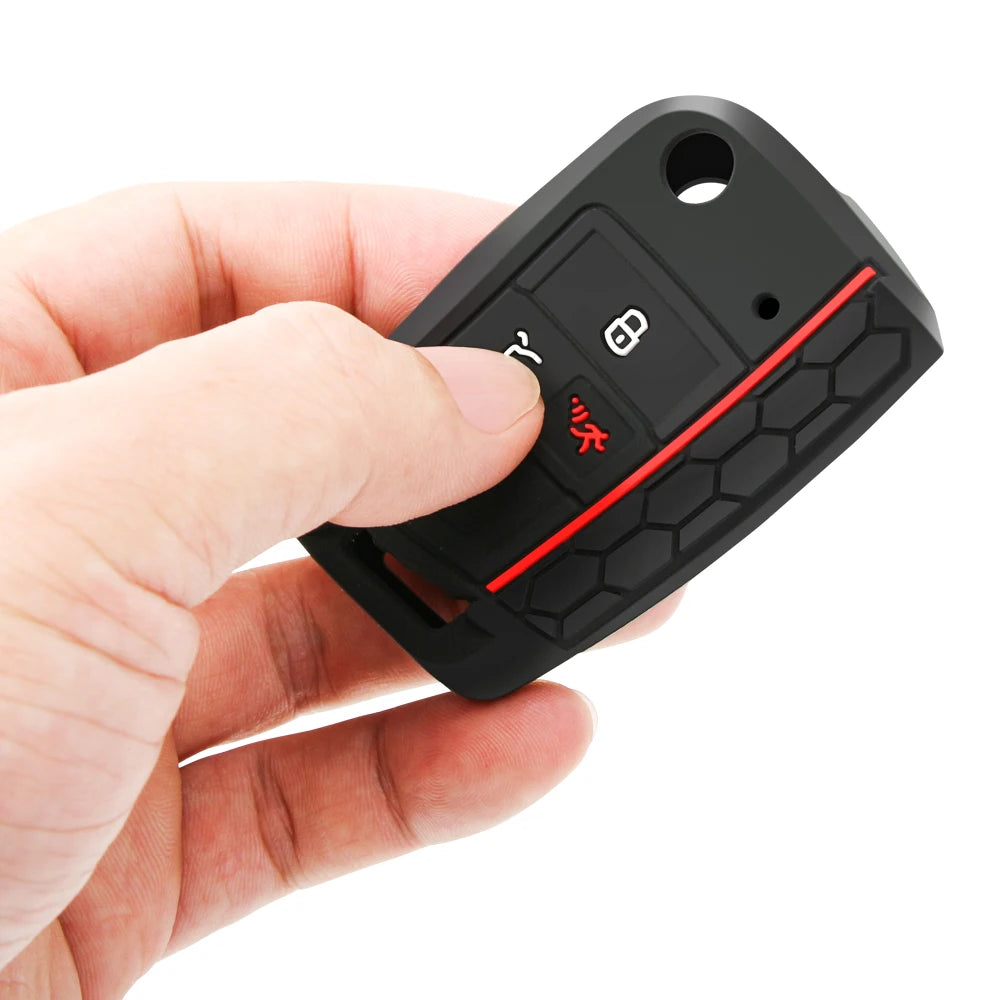 A hand holds a black silicone car key fob cover with a red accent, showing the protective case design.