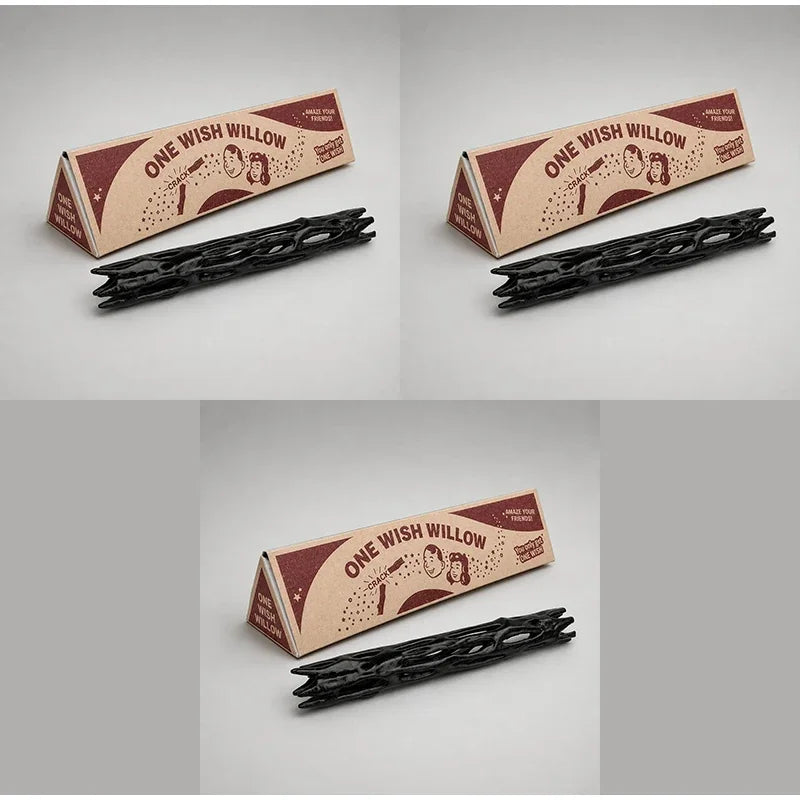 A black willow wood wishing stick with a gift box featuring a design of a face and text.