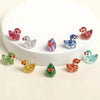 A collection of ten glitter resin duck figurines in various colors displayed on a white surface.