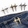 A set of gold-toned Y2K star waist tightener clips for jeans displayed against a dark denim background.