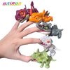 A hand is holding several mini finger dinosaur toys, including a purple, orange, gray, and green tyrannosaurus figurine.