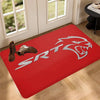 A red anti-slip doormat featuring a silver stylized lion head design on a wooden floor.