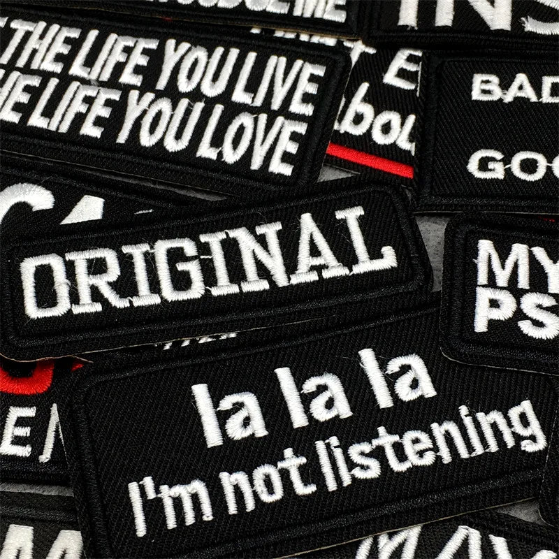 A collection of black text embroidery patches featuring phrases like THE LIFE YOU LIVE and ORIGINAL