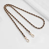 A close-up of a brown leather metal chain strap with a gold-toned buckle lying on a white surface.