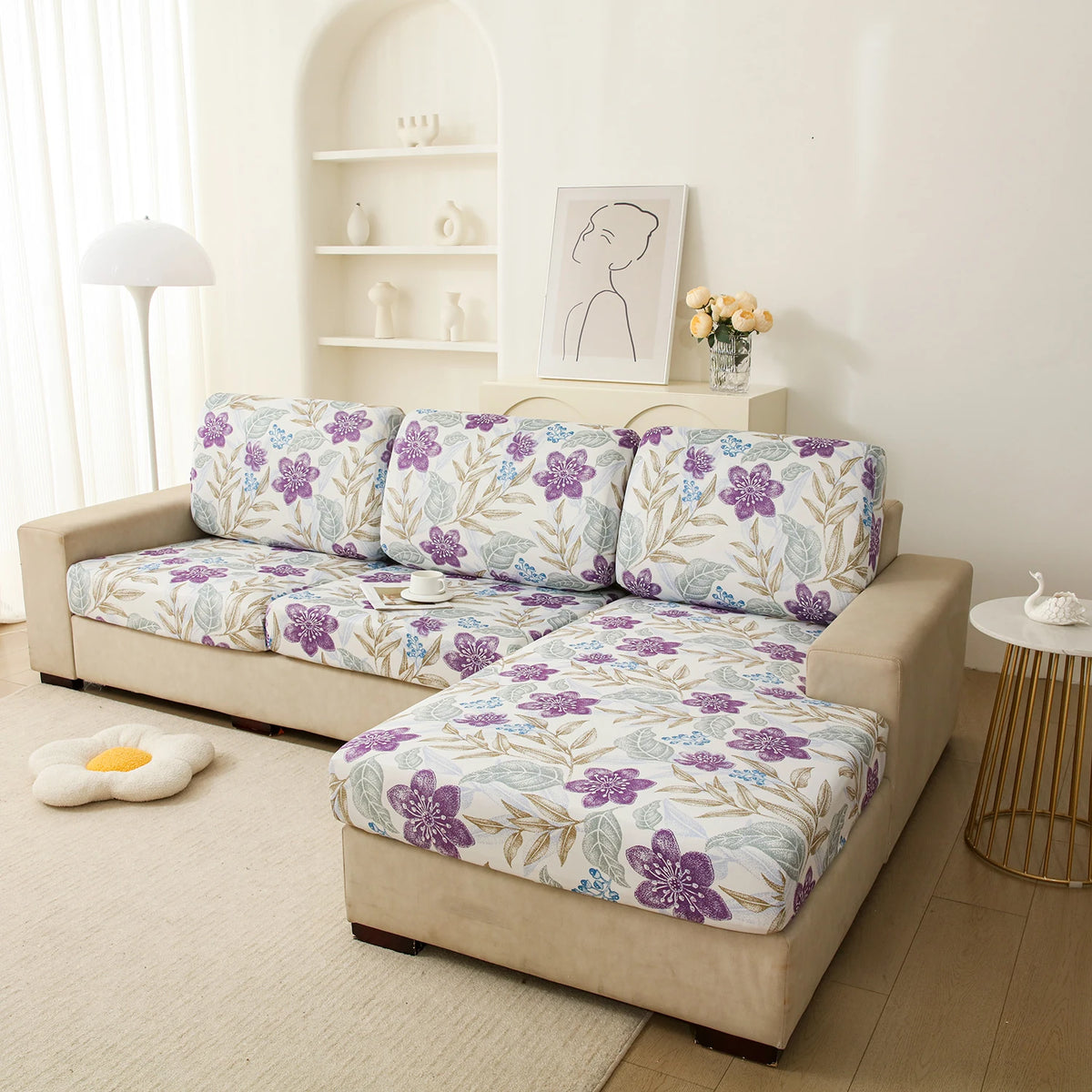 A beige floral elastic sofa cover is displayed on a light-colored sofa in a bright room.