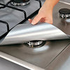 A hand places a silver silicone liner onto a gas hob surface.