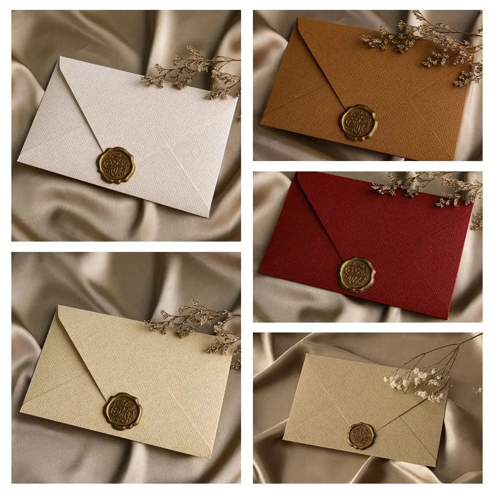A set of linen texture retro envelopes in beige and red with gold sealing wax stickers displayed on draped fabric.