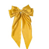 A golden yellow silk bow used as a hair accessory or ponytail holder.