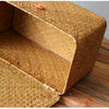 A close-up view of a woven rattan storage basket with a lid resting on a wooden surface.