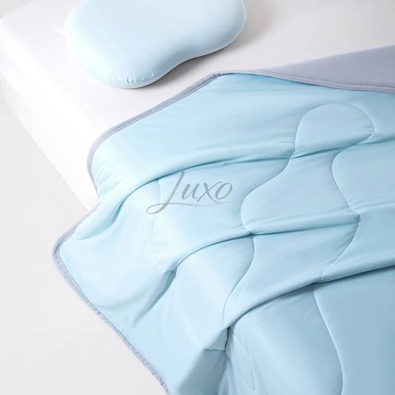 Light blue quilted ice silk cooling blanket folded on a white surface.