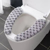 A plush winter toilet seat cushion cover with a gray and white patterned fabric is shown inside a white toilet bowl.